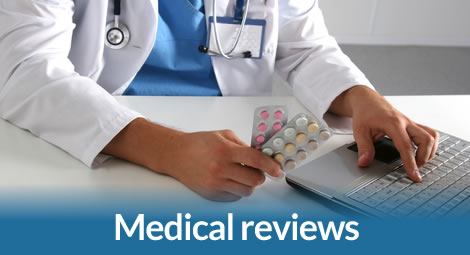 Doctor at laptop with pills reviewing medication